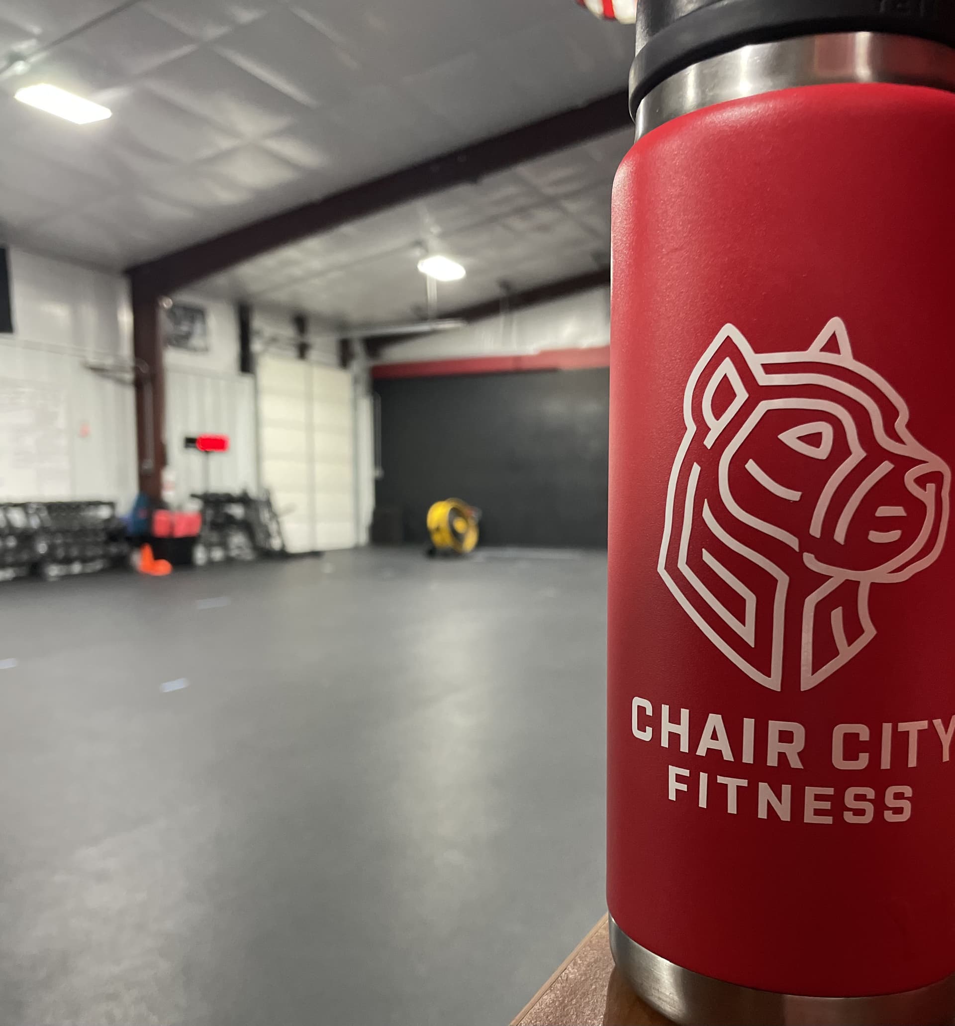 A member at Chair City Fitness smiles while lifting a barbell during a functional fitness class.